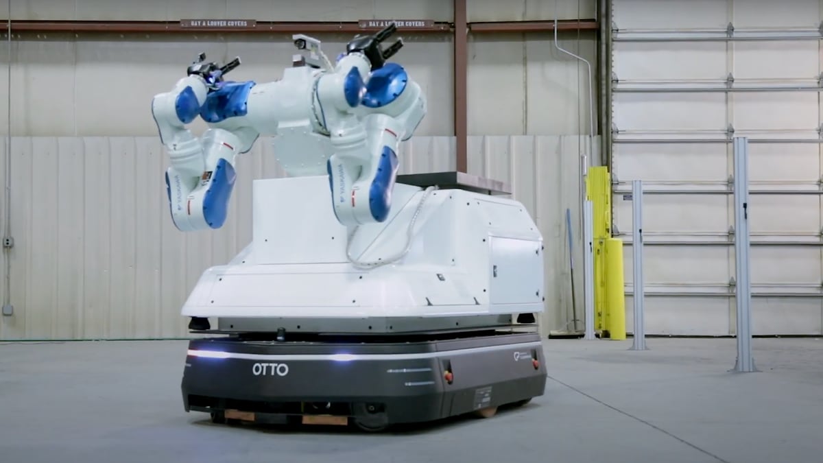 An OTTO autonomous mobile robot carrying a two-armed robot across an open plant floor