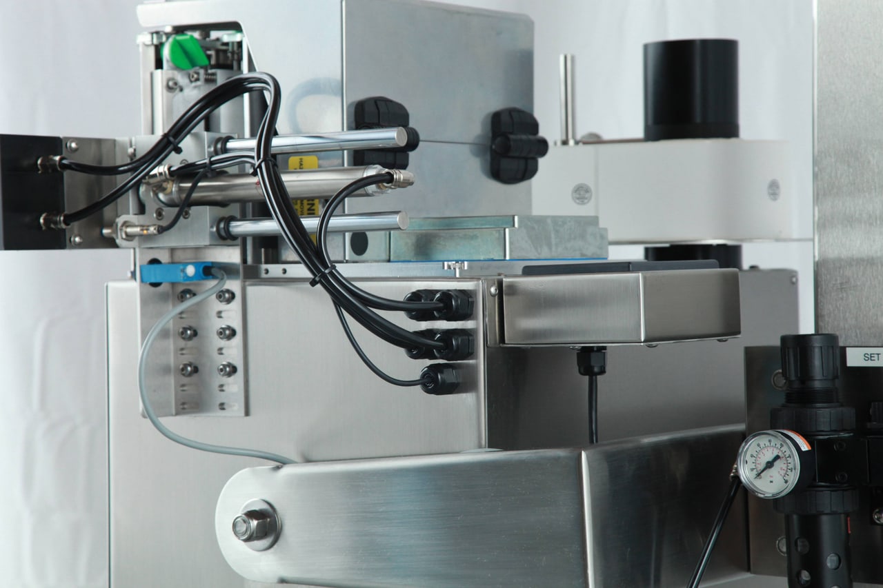 Close-up of the PI-85 applicator head, showing the tamp assembly, pneumatics and regulator