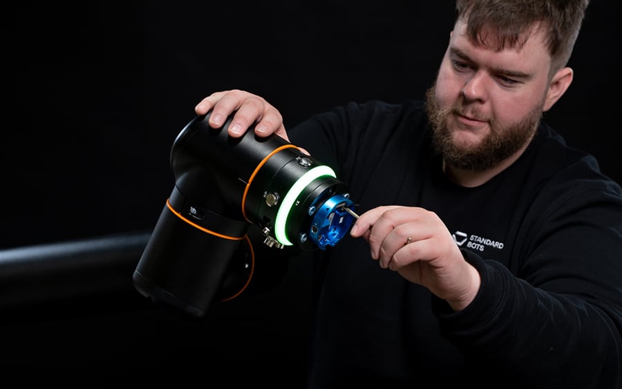 An engineer fitting an end-of-arm tool to a Standard Bots robot