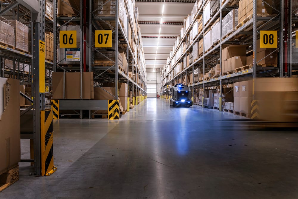 A Kärcher KIRA BR 200 scrubbing a warehouse floor